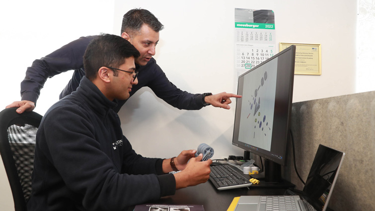 This image shows Melton Plastics owner Azam Khan looking at a computer screen with a colleague