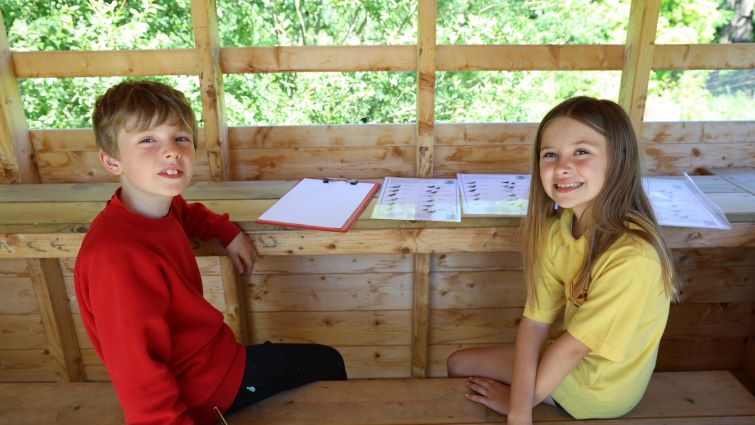 This image shows two pupils from Douglas Primary School who are participating in birdwatching at the school's own bird hide