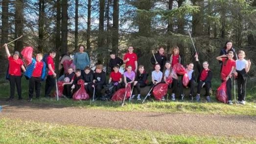 Cllr Robb, teacher Miss Laura Mooney and Hunter PS pupils with full bags of litter collected from park