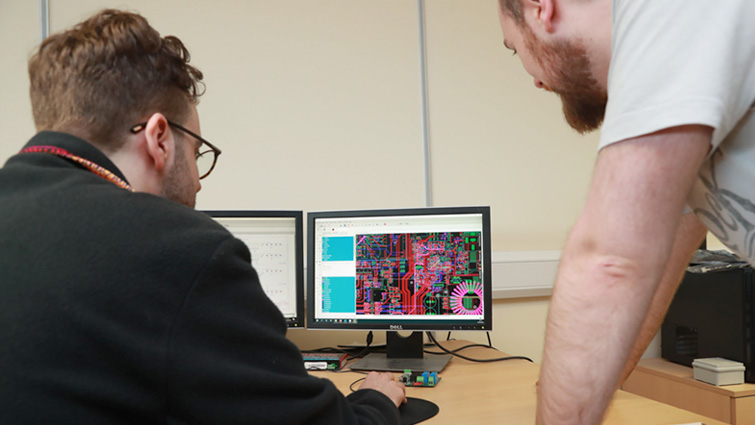This image shows two employees of Mage Control Systems looking at work on a computer