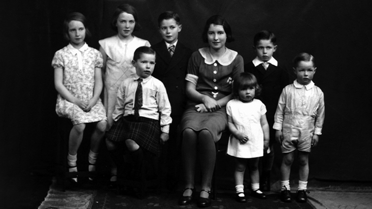 This photo is in black and white and shows Elizabeth as a child in a group with her seven brothers and sisters.